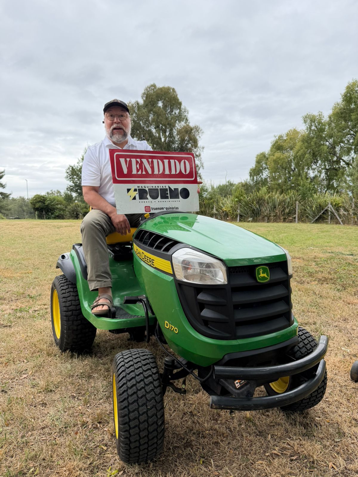 Cliente sobre un tractor cortacésped verde con un letrero de vendido.