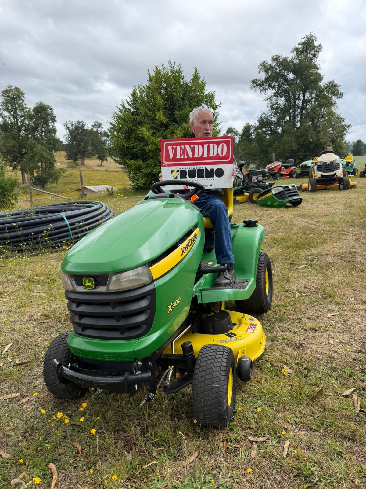 Cliente detrás de un tractor cortacésped verde con un letrero de vendido.