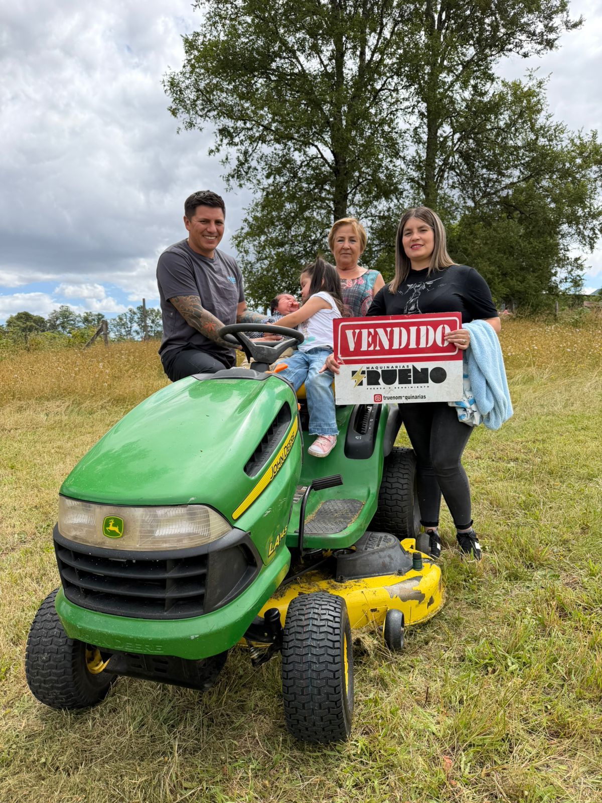 Clientes junto a un tractor cortacésped verde en terreno.