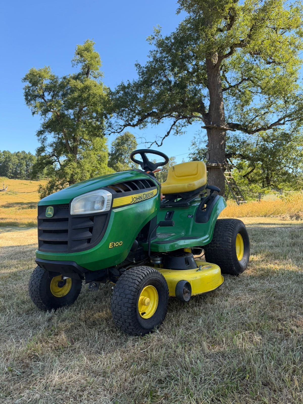 Segundo ángulo de un tractor cortacésped verde y amarillo en terreno.
