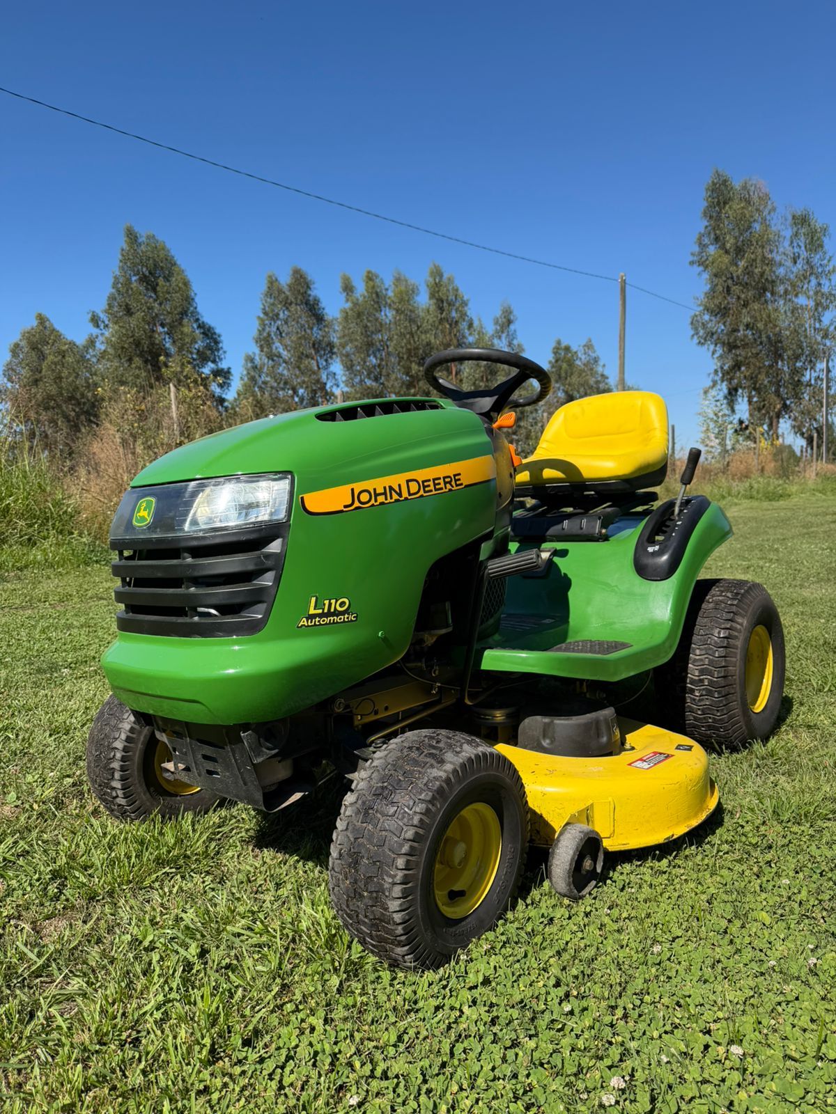 Tractor cortacésped verde y amarillo visto de cerca en terreno.